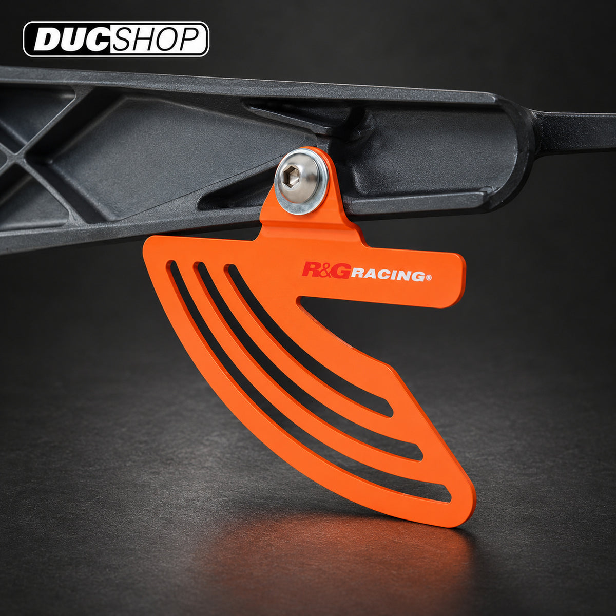 Orange R&G toe and chain guard installed at a swingarm mount; representative finish for TG0011BK Black | ducshop.com